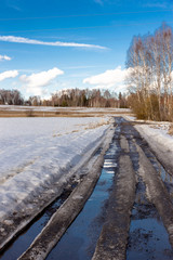 spring landscape, melting snow on the road and field in the countryside
