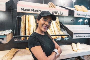Beautiful latin woman serving bread in pastry shop.