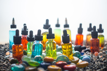 Vape concept. Beautiful colorful vape liquid glass bottles outdoor on stones. Useful as background...