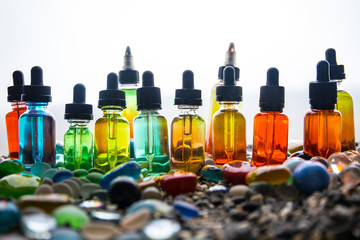 Vape concept. Beautiful colorful vape liquid glass bottles outdoor on stones. Useful as background...