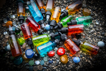 Vape concept. Beautiful colorful vape liquid glass bottles outdoor on stones. Useful as background...
