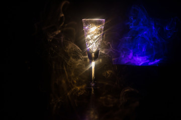 Closeup wine glass with fog at dark background. Beautiful glass with smoke and light.