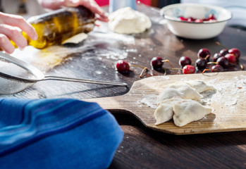 guy in his kitchen preparing dumplings with cherries.He uses a bottle instead of a rolling pin