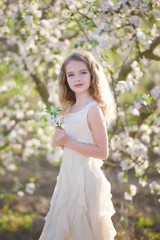 Obraz na płótnie Canvas Gorgeous blonde girl standing near blossom tree and smiling. Girl near tree. Blonde girl outdoor smiling. Girl in garden. Young female in blossoming orchard. Spring concept. 