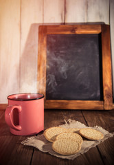Morning coffee with some cookies and aged wooden blackboard on rustic background