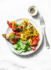 Healthy vegetarian snacks - turmeric baked cauliflower and marinated pepper, goat cheese, whole grain bread sandwiches on a light background, top view
