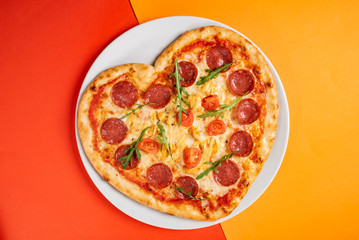 Heart shaped pizza with meat and vegetables. Food concept of romantic love for Valentines Day.