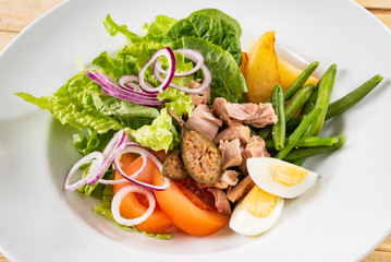 tuna salad with egg, tomatoes, red onions and green beans, wooden background