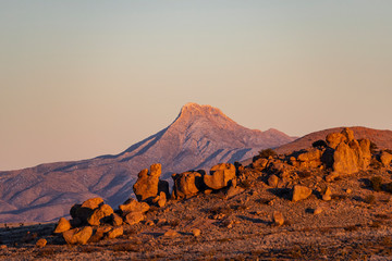 An iconic mountain peak bathes in golden hour light during sunset in the desert - 259945841