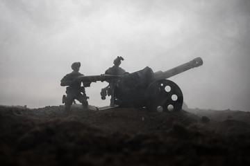 Battle scene. Silhouette of old field gun standing at field ready to fire. With colorful dark foggy...