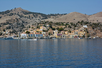Fototapeta na wymiar View of beautiful bay with colorful houses on the hillside of the island of Symi. Greece