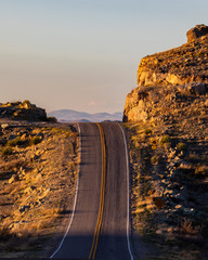 A lonely road over a big hill in the desert, at golden hour.