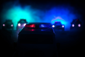Plakat Police cars at night. Police car chasing a car at night with fog background. 911 Emergency response pSelective focus