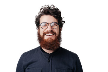 Close up smiling young businessman wearing eyeglasses, looking at the camera against white wall background