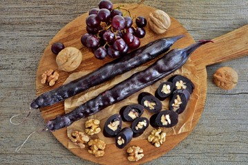 Caucasian delicacy churchkhela with grapes and walnuts on a wooden background close-up.