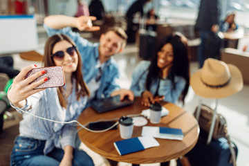 Three tourists makes selfie on phone in airport
