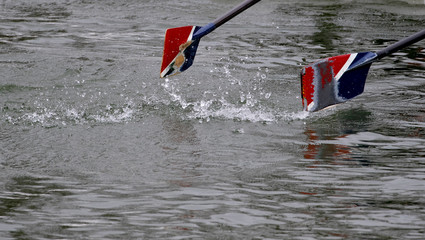 Oar of boat touching water and causing splashes and ripples