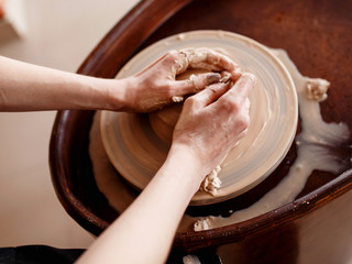 Hands sculpt new utensil on a pottery wheel