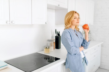 Fototapeta na wymiar Woman poses on kitchen with snow-white interior