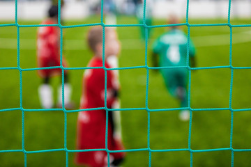Junior Sports Soccer Background. Soccer Goal Net and Blurred Youth Players in the Background