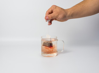 hand with tea bag and glass cup with boiling water 
