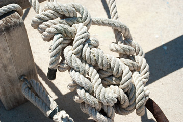 Fototapeta na wymiar Sea knot in port. Marine equipment background. Navy rope. Summer sail.