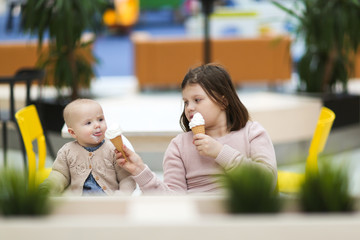 sisters eat ice cream in cafe shopping in center