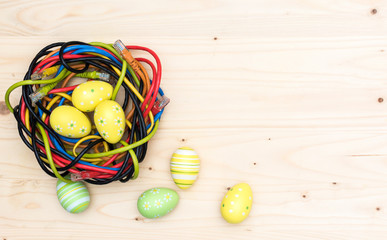 Easter eggs and nest of internet cables on wooden board