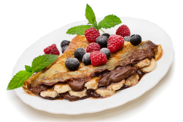 Homemade crepes served with chocolate cream, fresh blueberries and raspberries, powdered sugar on a white background