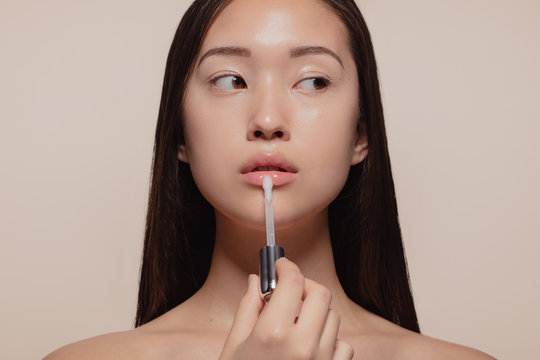 Woman applying transparent lip gloss - Powered by Adobe