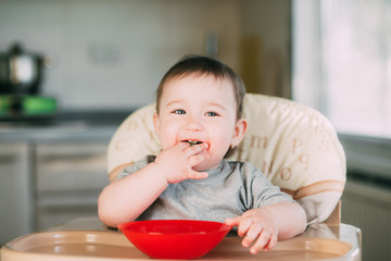 little girl on a high chair eating kiwi