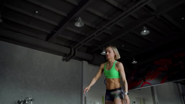 Young strong woman with perfect fitness body in sportswear exercising with medicine ball at gym. Girl doing crossfit training. Slow motion. Close up