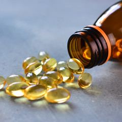 Omega 3 vitamins pills scattered from the bottle, cropped