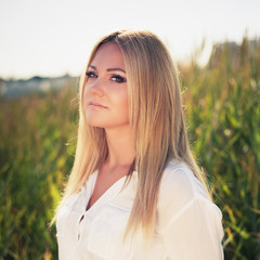 young beautiful woman poses in green thickets, looks in the camera