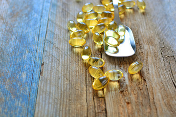 Scattered Omega 3 vitamins capsules on a wooden background
