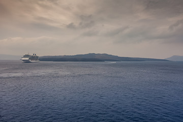 Obraz premium Panorama of Santorini on a cloudy day, with cruise ship waiting in the harbor