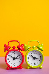 green and red vintage alarm clock on yellow color background.