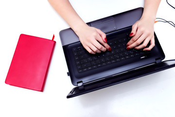 Hands on the laptop keyboard, top view on a white table.