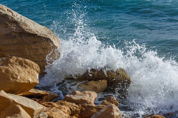 sea wave with splashes hits coastal rocks