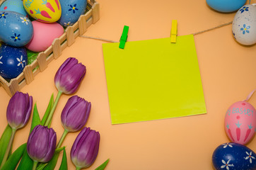 Easter greeting card with eggs and tulips on orange background. Easter decoration