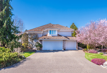 Beautiful exterior of newly built luxury home. Yard with green grass and walkway lead to ornately designed covered porch and front entrance.
