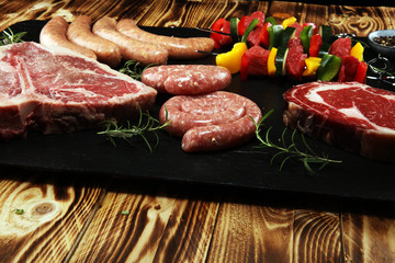 Assorted delicious raw meat with vegetable on a barbecue with t-bone steak, sausages and meat Skewers.