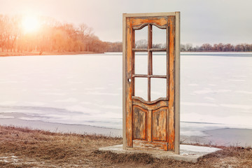 free-standing door in nature against the backdrop of a frozen lake in winter. door to another world