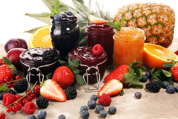 assortment of jams, seasonal berries, plums, mint and fruits in glass jar