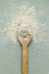 Top view of cosmetic clay powder in a wooden spoon 