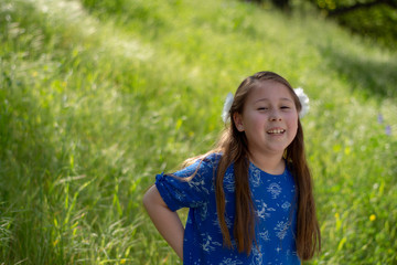 Little Girl in Blue Dress Smiling in Front of Field with Flowers