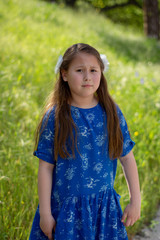 Little Girl in Blue Dress making worried or disgusted face in front of green field