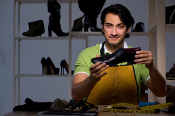 Young shoemaker in workshop at night 