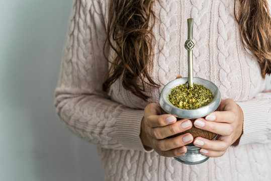 Young woman drinking traditional Argentinian yerba mate tea from a calabash gourd with bombilla stick 