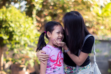 Asian mother kissing her daughter with love